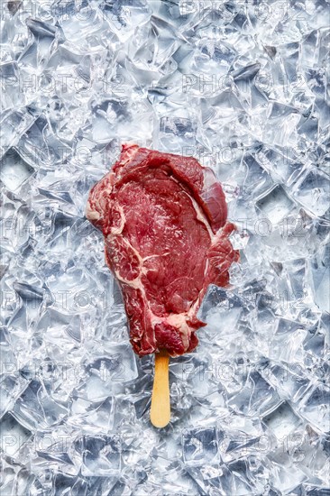 Raw beef rib steak with ice-cream stick on pieces of ice