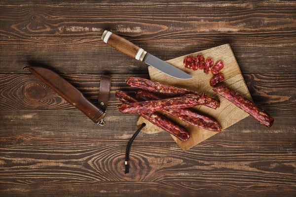 Overhead view of dried jerked deer and pork sausage on wooden background