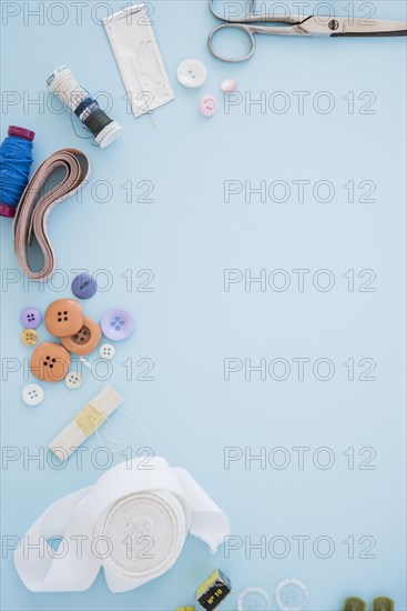 Scissor buttons needles spool measuring tape ribbon blue backdrop