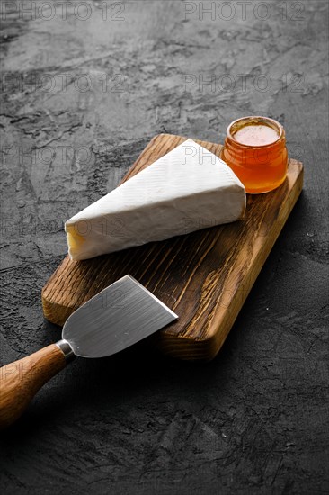 Piece of soft brie or camembert cheese on cutting board