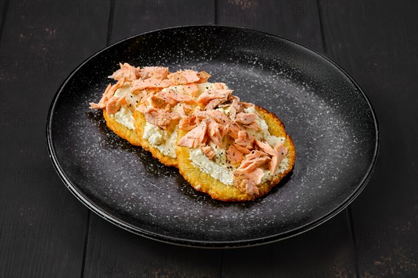 Fried potato patties with greek yogurt and salmon on a plate