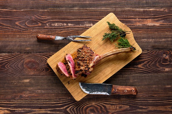 Overhead view of medium rare cowboy steak on wooden cutting board