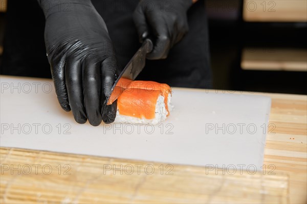 Chef cuts salmon rolls with knife