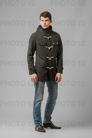 Full length portrait of handsome man in warm woolen coat posing in studio