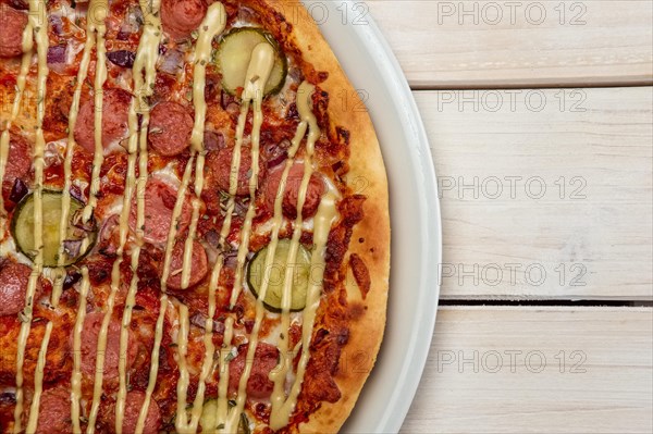 Top view of pizza with thin sausage and pickled cucumber