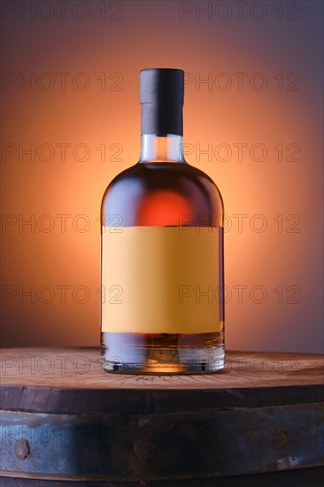 Blended malt scotch whisky on top of the barrel over blue and orange gradient background