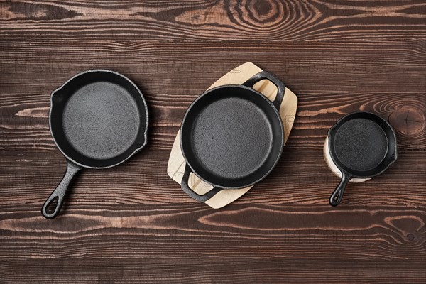 Three empty mini cast-iron skillets on wooden table