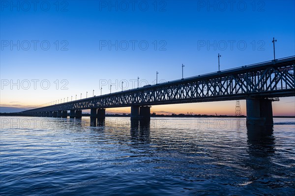 Giant bridge spanning over the Amur river at sunset