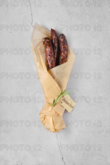Overhead view of dried sausage made of venison spicy meat and lard in wrapping paper
