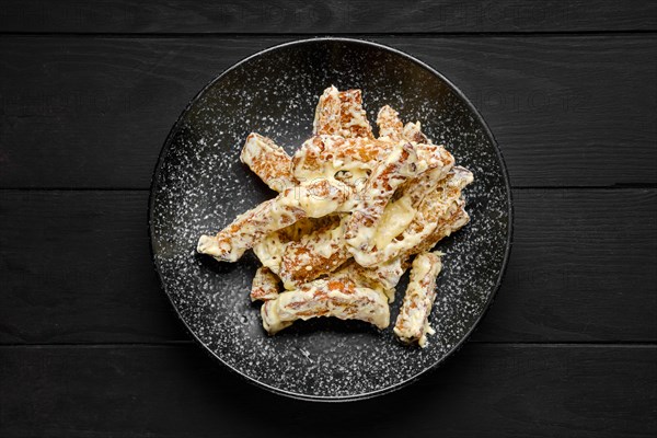 Overhead view of salty bread sticks covered with melted cheese on a plate