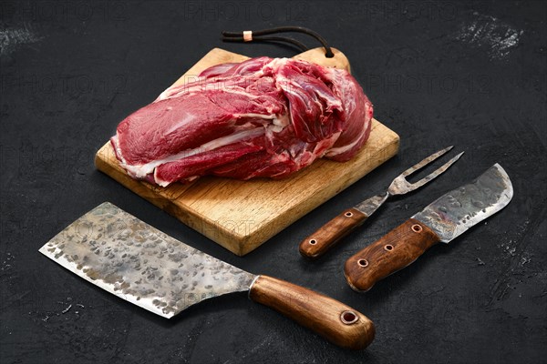 Overhead view of raw lamb shoulder without bone on wooden cutting board