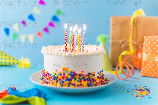 Decorative cake with burning candle blue background