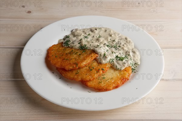 Traditional belorussian potato pancakes draniki with mushroom sauce on a plate