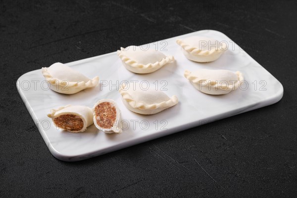 Frozen dumplings stuffed with beef meat and provencal herbs on marble serving plate
