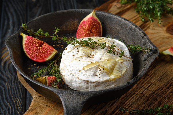 Closeup view of baked in oven camembert cheese and figs ready for baking on frying pan