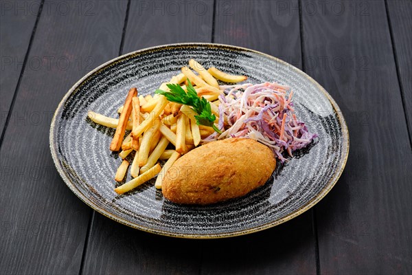 Kiev cutlet with american fries and red cabbage with carrot as a garnish