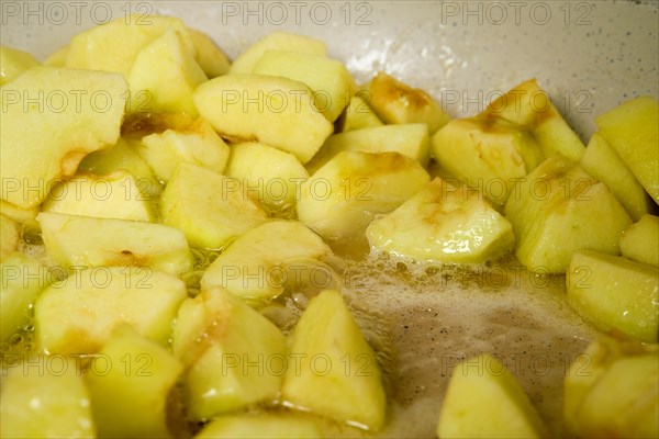 Slices of green apples caramelizing in frying pan with sugar