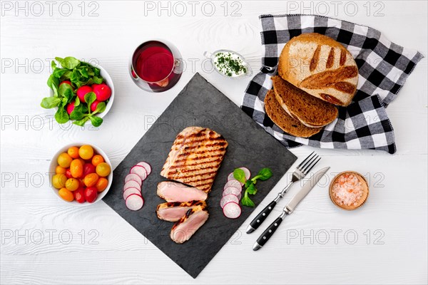 Grilled beef steak medium rare on stone board with fresh vegetables and glass of red wine. View from above