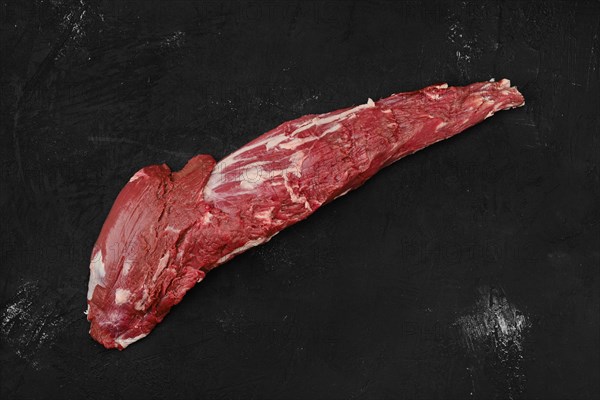 Overhead view of raw beef tri-tip loin on black background