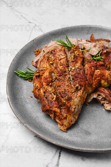 Closeup view of pulled lamb shoulder meat baked in oven with potato and carrot on marble table