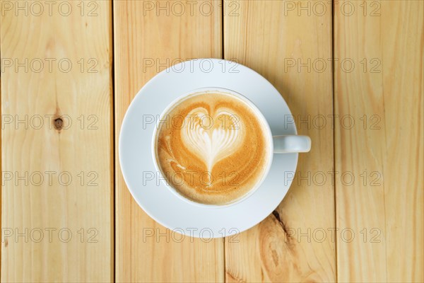 Overhead view of cappuccino in ceramic cup on wooden table