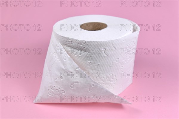 Roll of toilet paper on pink background