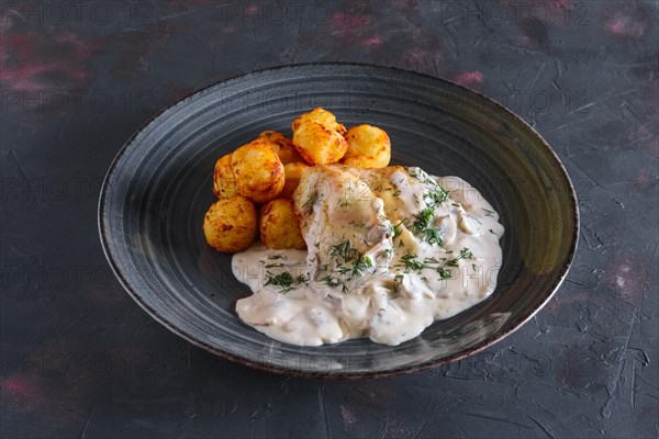 Fried potato balls and white fish fillet with creamy sauce