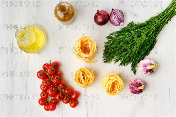 Overhead view of raw tagliatelle with spice and herbs on wooden table