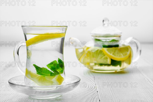 Antioxidant hot drink with lemon and mint in transparent tea pot and glass