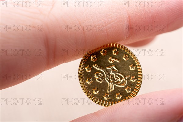 Fake gold coins in hand between fingers on canvas
