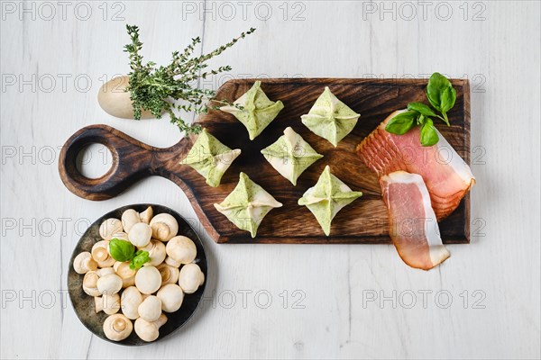 Top view of dumplings stuffed with smoked ham and mushrooms on wooden serving board