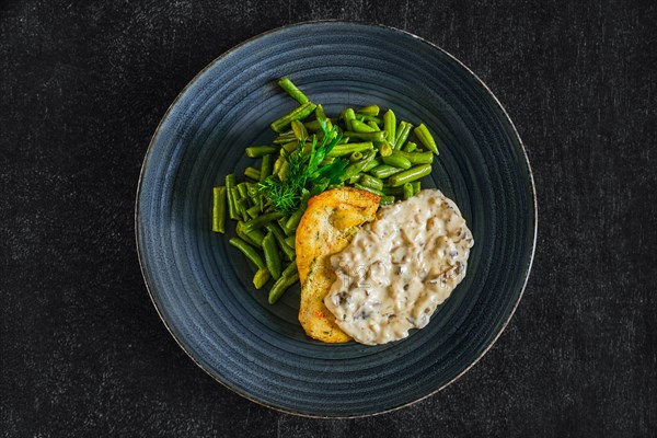 Top view of fried chicken fillet with green beans and mushroom sauce