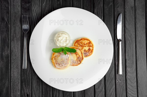 Top view of cottage cheese fritters with sugar powder on a plate