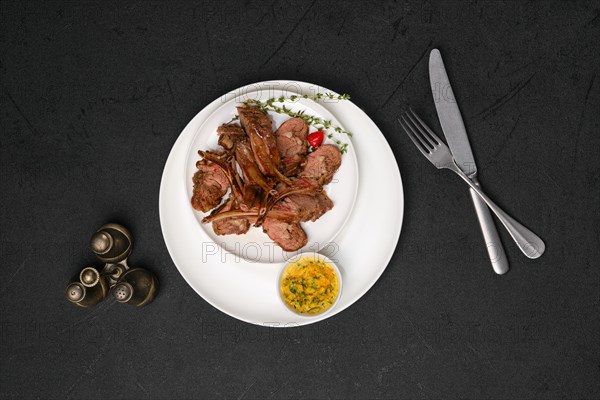 Overhead view of grilled rack of lamb on a plate with spicy sauce