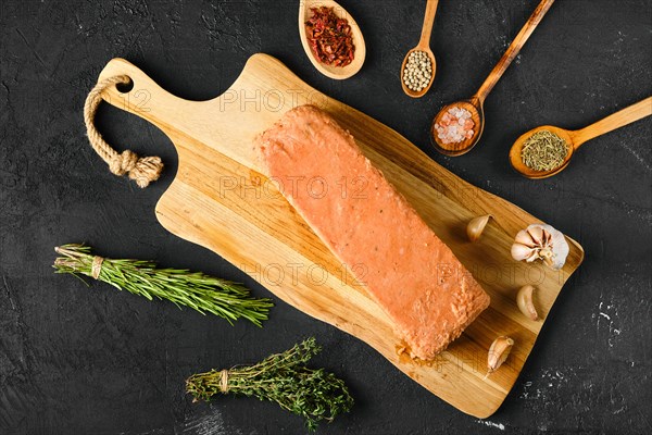 Overhead view of raw pieces of salmon pressed in briquette with spice and herbs