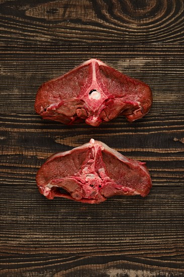 Overhead view of raw fresh deer backstrap over dark wooden background