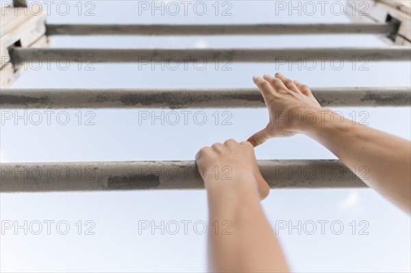 Low angle woman climbing metal bars