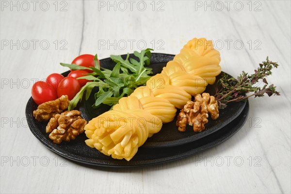 Smoked braided cheese with walnuts and tomatoes on a plate