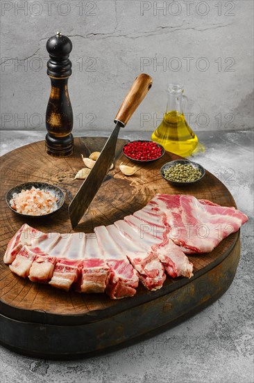 Raw lamb flap ribs with ingredients for cooking on wooden log