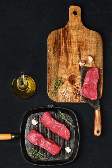 Top view of raw boneless beef strip steak ready for frying on black background