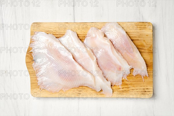 Overhead view of raw fresh peeled stingray wings on wooden cutting board
