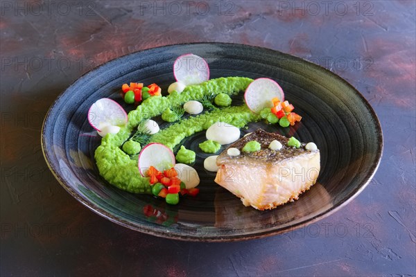 Fried salmon with pea mash decorated with radish and peas