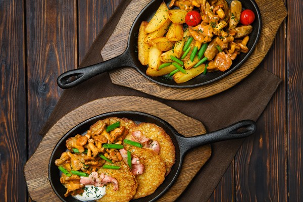 Top view of potato wedges with chanterelles and pork in cast iron skillet