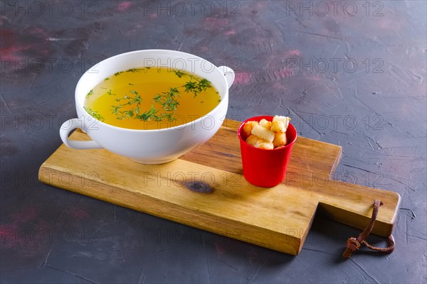 Plate with clear soup and pieces of white bread crouton