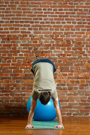 Athletic man doing exercises for the balance on rubber ball. Fitness workout