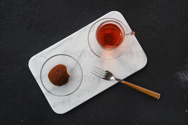 Top view of chocolate biscuit dough cake and a cup of tea on a table