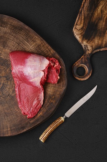 Top view of raw ribeye cap roll on wooden on chopping slab