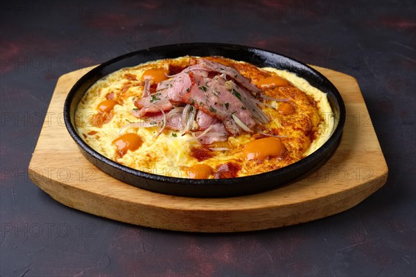Omelette with bacon and fried onion on cast-iron pan