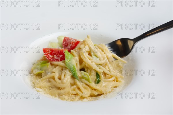 Fork in plate with pasta served with bacon and ham