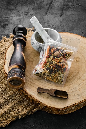 Wooden cross section with set for mulled wine spices in plastic package and stone mortar and mill